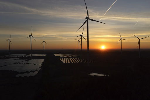 FILE - Wind turbines operate as the sun rises at the Klettwitz Nord solar energy park near Klettwitz