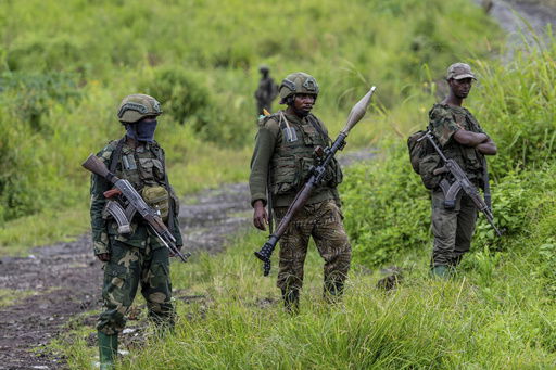 FILE - M23 rebels stand with their weapons in Kibumba
