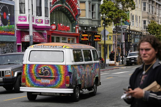 A tour van featuring a painting of musician Jerry Garcia travels through Haight Street in San Francisco