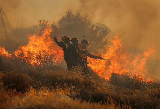 Firefighter uses a hose as the try to extinguish the blaze near the town of Ierapetra on the south coast of Crete island