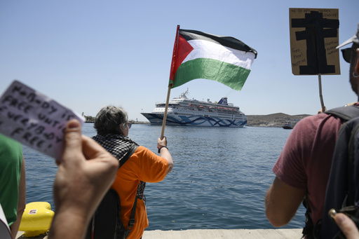 A protester waves a Palestinian flag as people demonstrates in front of a cruise ship carrying Israeli tourists and trying to approach the Aegean Sea island of Syros