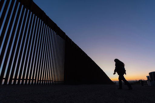 FILE - A volunteer walks along a road next to the border wall separating Mexico and the United States in Jacumba Hot Springs