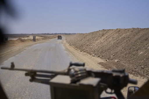 Israeli army vehicles transport a group of soldiers and journalists along the Morag corridor in southern Gaza on June 8