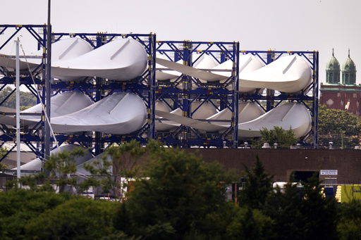 FILE - Giant wind turbine blades for the Vineyard Winds project are stacked on racks in the harbor