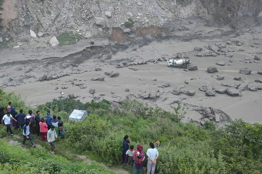People watch the damage caused by flooding on the Bhotekoshi River 120 kilometers (75 miles) north of Kathmandu