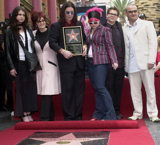 FILE - Metal-rock star Ozzy Osbourne holds a replica of his new star on the Hollywood Walk of Fame as he poses with his family during a ceremony on April 12