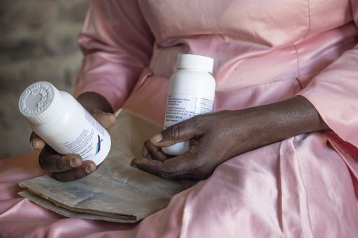 FILE - Florence Makumene holds HIV medication that she received through funding from the U.S. President's Emergency Plan for AIDS Relief (PEPFAR)