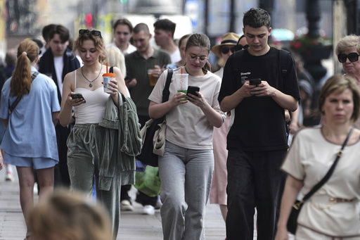 Pedestrians look at their phones while walking through St. Petersburg