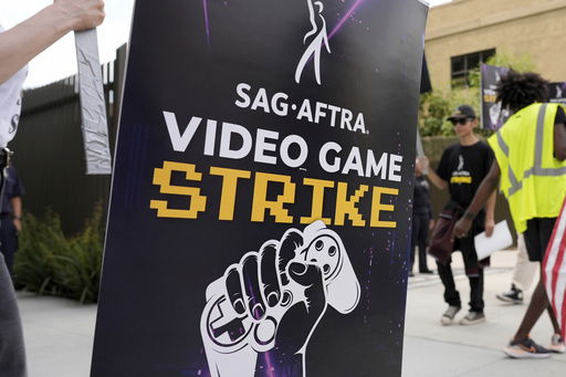 FILE - A picketer holds a sign for the SAG-AFTRA video game strike at Warner Bros. Games headquarters on Aug. 1