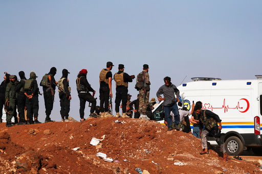 A convoy of ambulances and buses arrives at a checkpoint in the village of Busra al-Harir