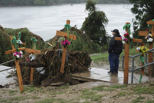 FILE - Rain falls as Irene Valdez visits a make-shift memorial for flood victims along the Guadalupe River