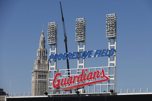 FILE - Workers finish installing the Cleveland Guardians sign above the scoreboard at Progressive Field