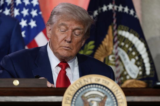 President Donald Trump signs executive orders after speaking during an AI summit at the Andrew W. Mellon Auditorium