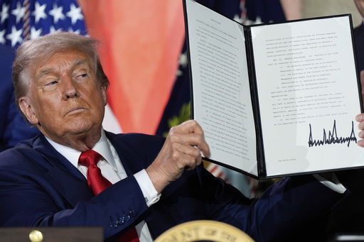 President Donald Trump holds a signed executive order after speaking during an AI summit at the Andrew W. Mellon Auditorium