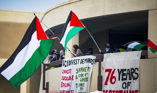 FILE - Pro-Palestinian protesters wave flags from the second level of the Physical Sciences Lecture Hall after they took over the building at the University of California