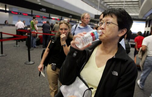 A passenger takes a sip of water before throwing away the bottle at a security checkpoint at San Francisco International Airport.