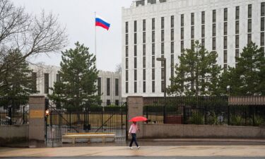 A pedestrian walks with an umbrella outside the Embassy of the Russian Federation