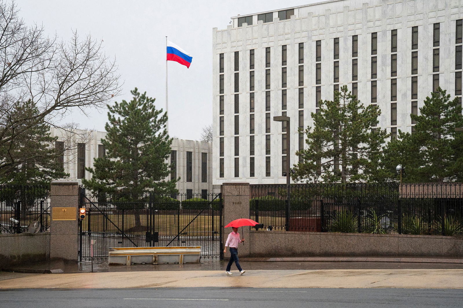 <i>Tom Brenner/Reuters/File via CNN Newsource</i><br/>A pedestrian walks with an umbrella outside the Embassy of the Russian Federation