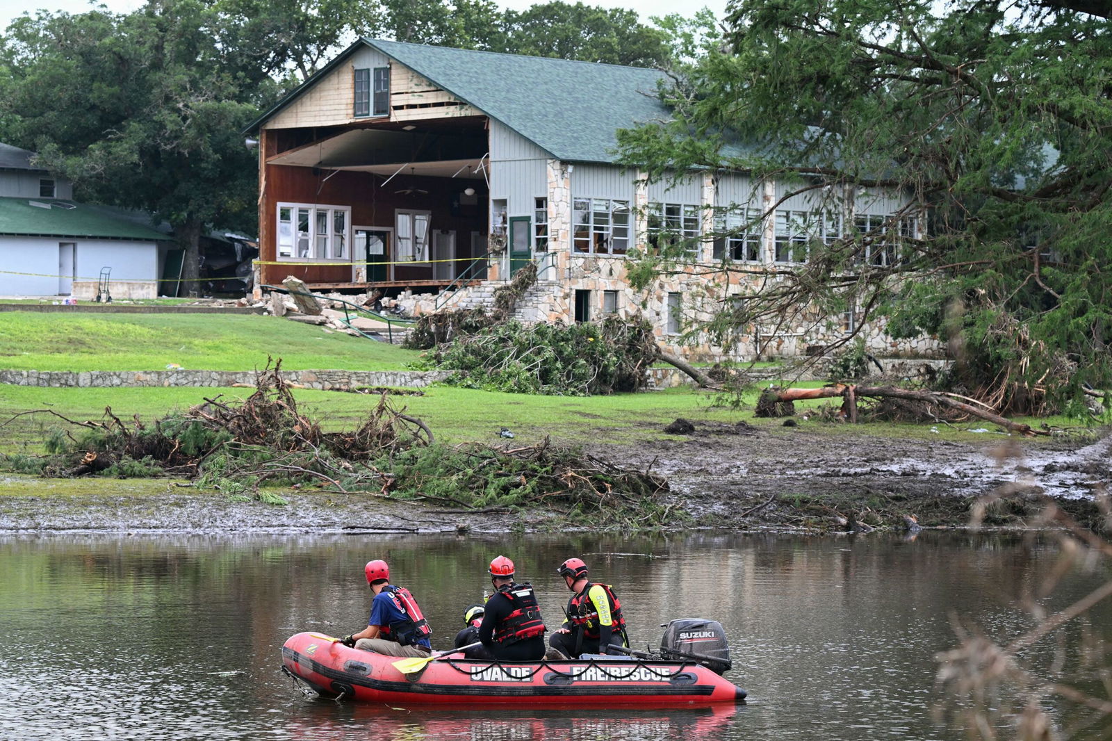 <i>Ronaldo Schemidt/AFP via Getty Images via CNN Newsource</i><br/>A search and rescue team looks for people along the Guadalupe River near a damaged building at Camp Mystic in Hunt
