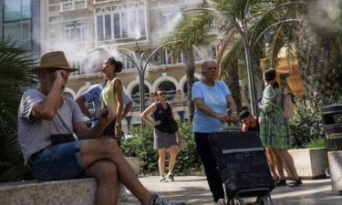 Pedestrians walk past a pharmacy sign showing 39 degrees celsius (86 Fahreneheit) as high temperatures hit Lisbon