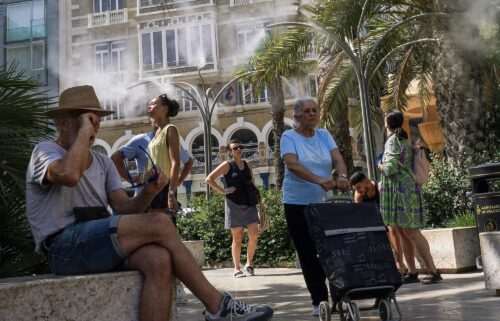 Pedestrians walk past a pharmacy sign showing 39 degrees celsius (86 Fahreneheit) as high temperatures hit Lisbon