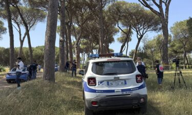 A police officer walks past a sealed-off area where forensic police work at the site of the discovery of the body of an infant and the infant’s mother