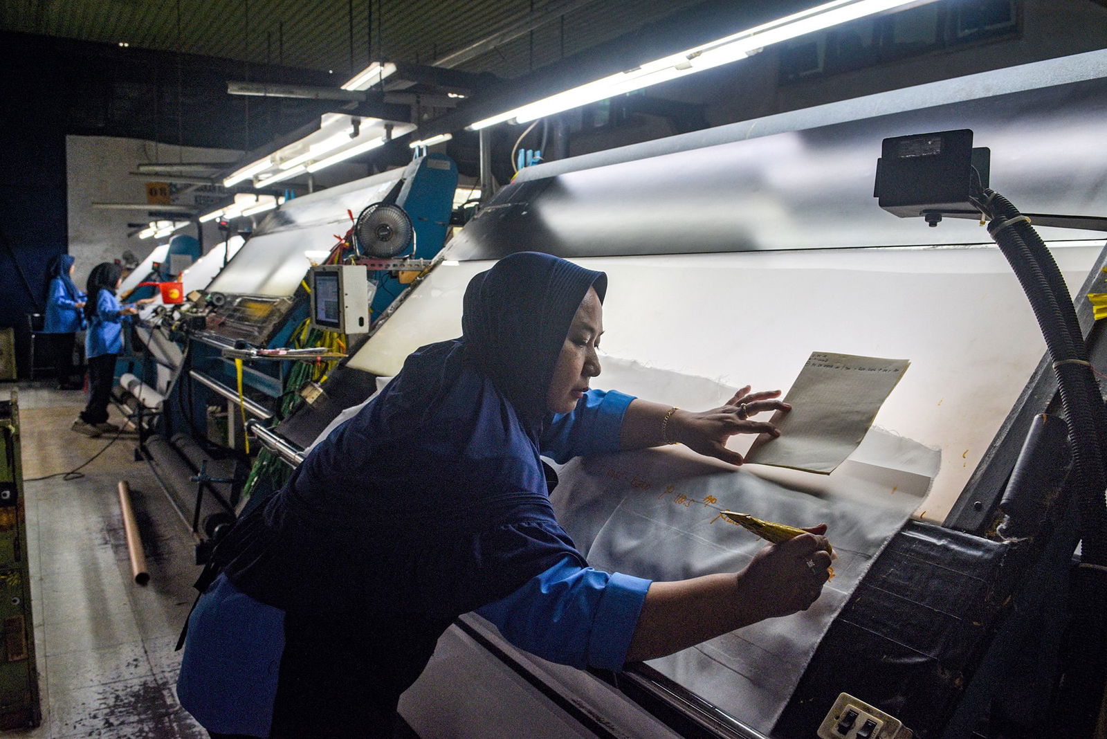 <i>Timur Matahari/AFP/Getty Images via CNN Newsource</i><br/>A worker inspects fabric for export before the dyeing process at the Trisula Textile Industries factory in Cimahi