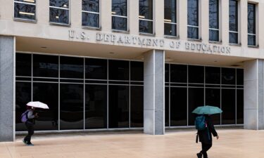 Workers leave the Department of Education building during a rain shower in Washington