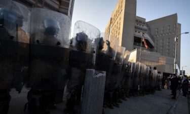 US Marines and National Guard troops stand in line protecting the entrance of the Metropolitan Detention Center as demonstrators gather in front of it following federal immigration operations