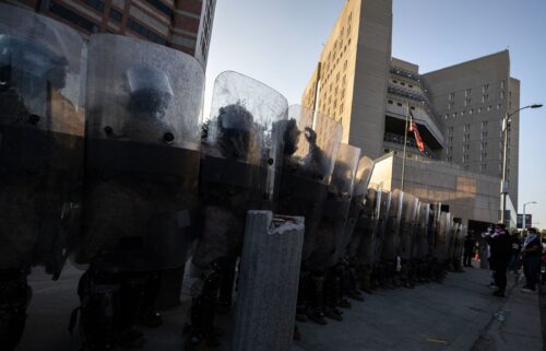 US Marines and National Guard troops stand in line protecting the entrance of the Metropolitan Detention Center as demonstrators gather in front of it following federal immigration operations