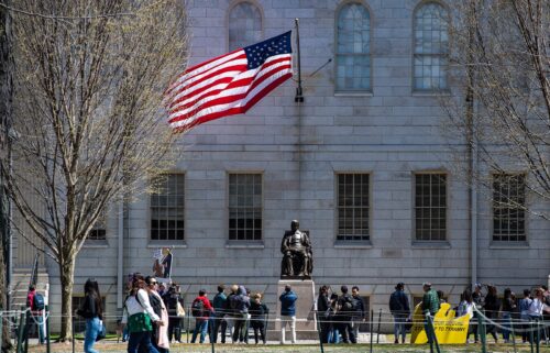 Demonstrators with signs stand around the John Harvard Statue in Harvard Yard after a rally was held against President Donald Trump's attacks on Harvard University at Harvard University in Cambridge