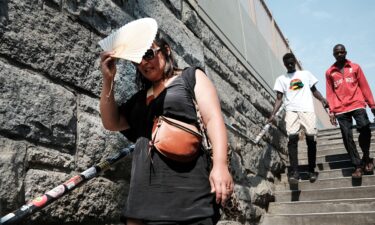 A woman shades herself from the sun as she tries to keep cool along the Brooklyn Bridge during a heat wave.