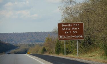 A roadside sign with exit directions to Devils Den State Park at Interstate 49