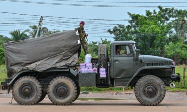 A Cambodian soldier stands on a truck carrying a Russian-made BM-21 rocket launcher travelling along a street in Oddar Meanchey province on July 26