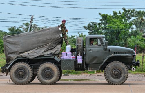A Cambodian soldier stands on a truck carrying a Russian-made BM-21 rocket launcher travelling along a street in Oddar Meanchey province on July 26