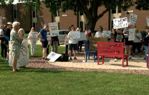 Protesters with signs gather outside the venue for Rep. Bryan Steil's town hall in Elkhorn