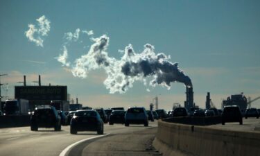Vehicles move along the The New Jersey Turnpike Way while a Factory emits smoke on November 17