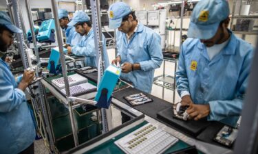 Employees work on a mobile phone assembly line in Noida