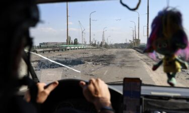 A car with volunteers drives over a damaged bridge after Russian air bomb attacks in Kherson