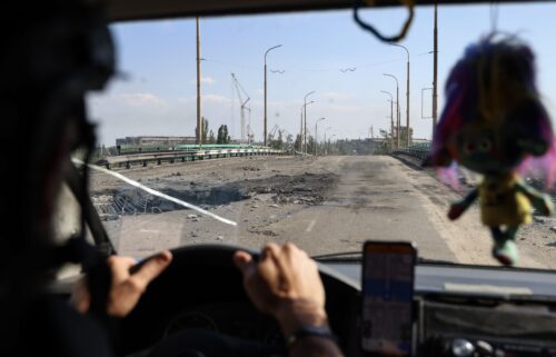 A car with volunteers drives over a damaged bridge after Russian air bomb attacks in Kherson