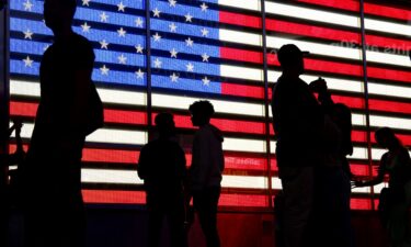 People stand in front of a US flag on a screen in Times Square in New York on September 19