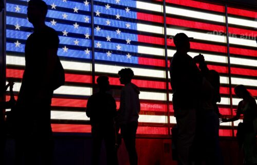 People stand in front of a US flag on a screen in Times Square in New York on September 19