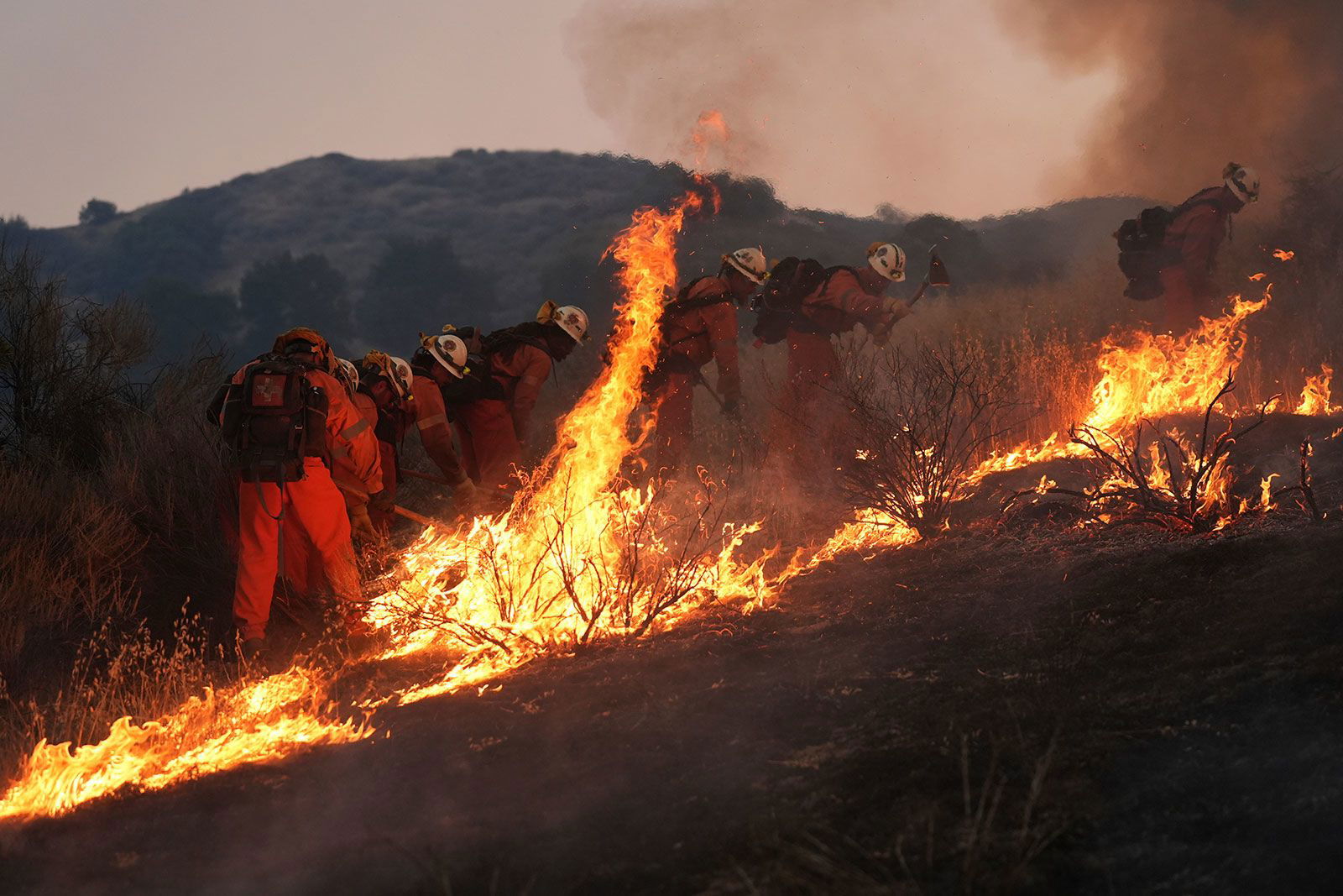 <i>Marcio Jose Sanchez/AP via CNN Newsource</i><br/>A resident rides a golf cart as he exits his property while the Canyon Fire burns on Thursday in Halsey Canyon