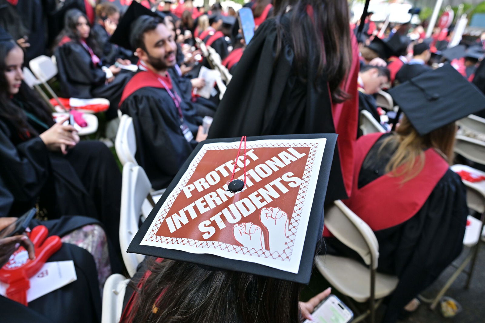 <i>Josh Reynolds/For The Washington Post/Getty Images via CNN Newsource</i><br/>A Harvard University graduate with a message in support of international students on her mortarboard sits with fellow students at the start of commencement exercises at Harvard University in Harvard Yard