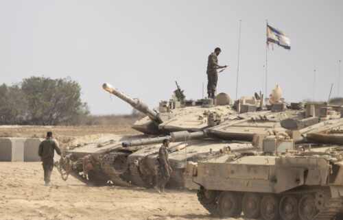 Israeli soldiers work near tanks in a gathering point near the border with the Gaza Strip