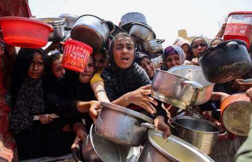 Palestinians gather to receive cooked meals from a food distribution center in Gaza City on August 13