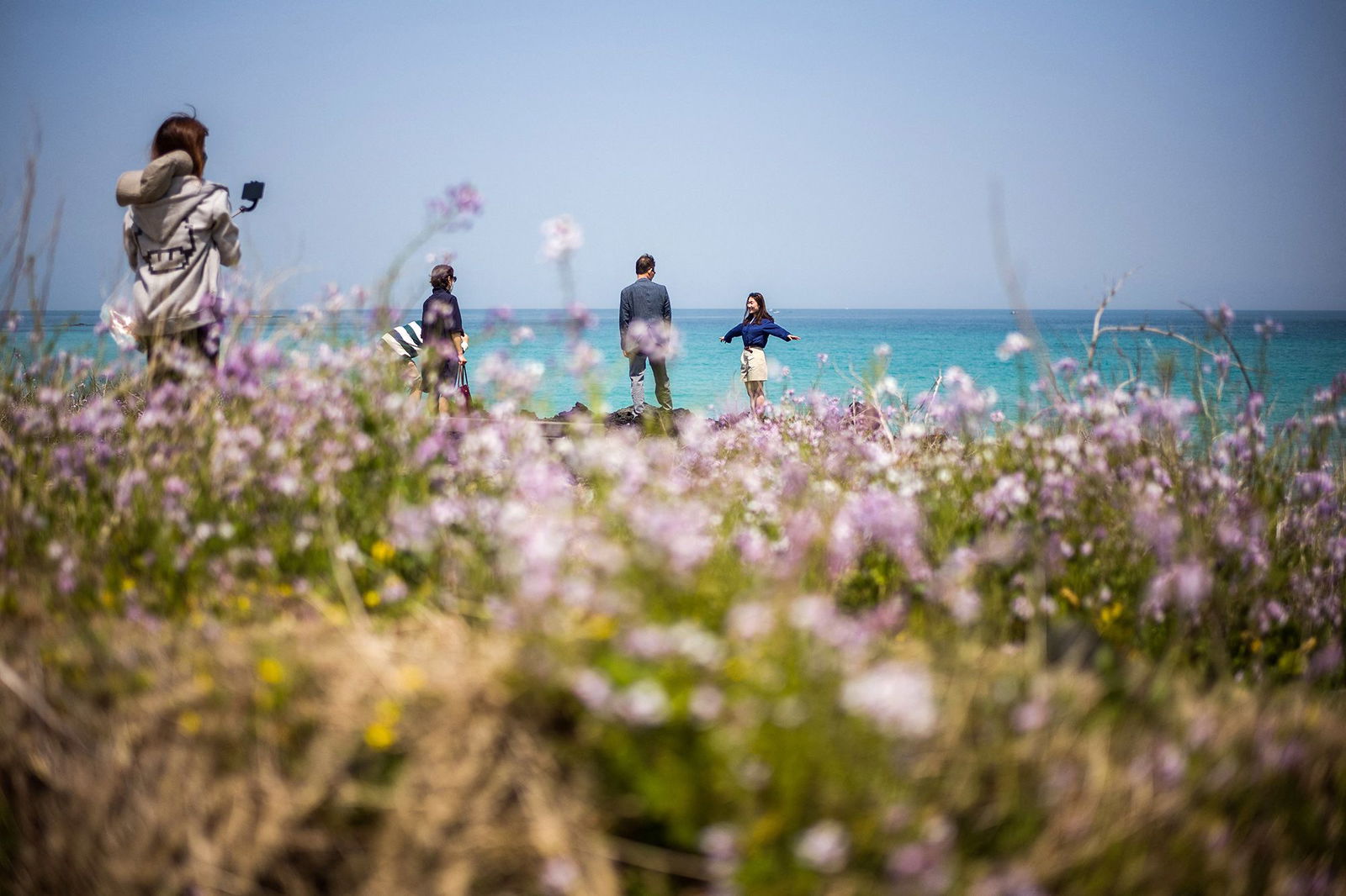 <i>Anthony Wallace/AFP/Getty Images via CNN Newsource</i><br/>Visitors take photos near Hamdeok Beach in Jeju City. The island of Jeju has issued a multi-language guide warning international visitors to behave following a string of viral tourist incidents and cases of disorderly conduct.