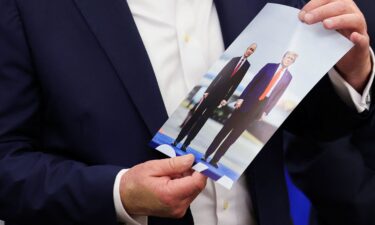 US President Donald Trump holds an image of him and Russian President Vladimir Putin