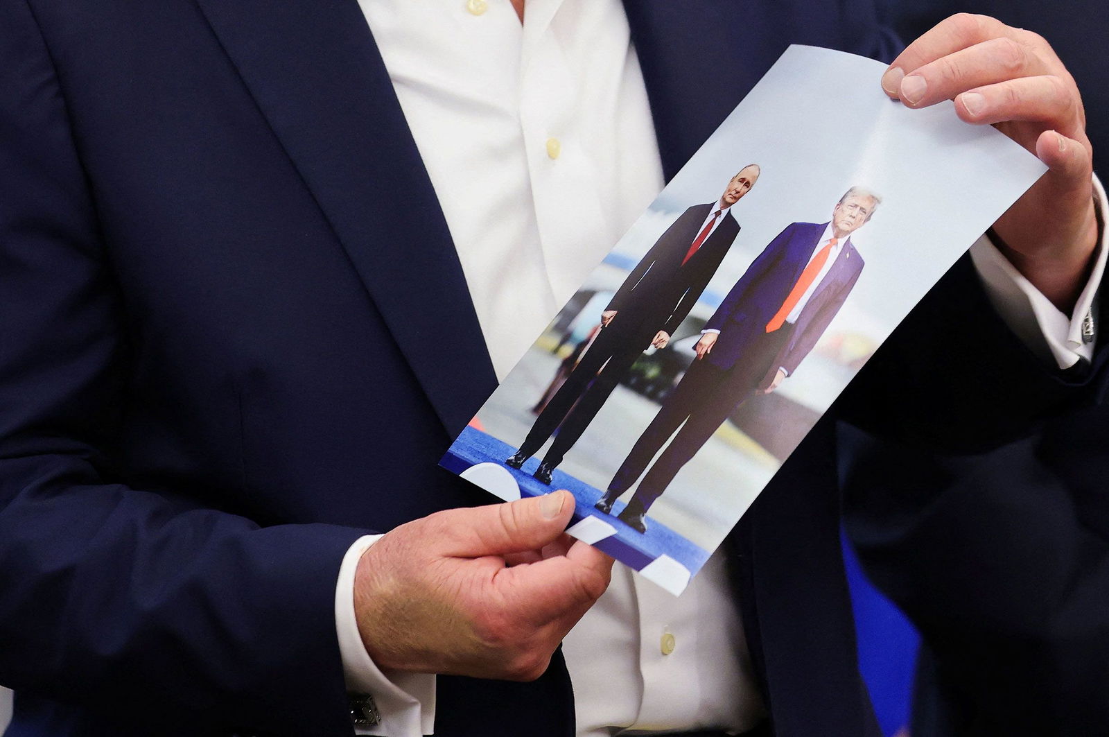 <i>Jonathan Ernst/Reuters via CNN Newsource</i><br/>US President Donald Trump holds an image of him and Russian President Vladimir Putin