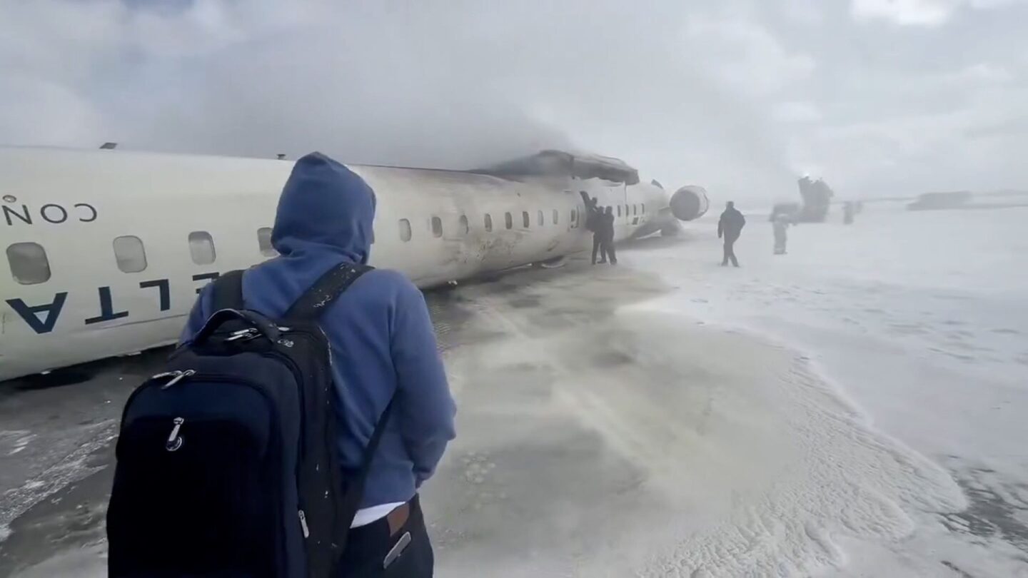 <i>John Nelson via CNN Newsource</i><br/>People evacuate from an overturned Delta Connection CRJ-900 aircraft